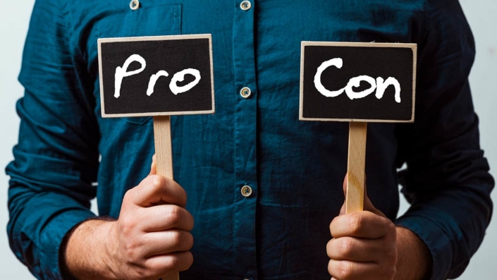 Photo of a man holding pros and cons cards Photo of a man holding pros and cons cards