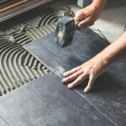 Photo of a worker carefully placing ceramic floor tiles on adhesive surface