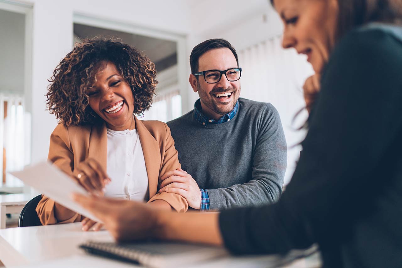 Photo of a happy married couple talking with financial advisor on a meeting in the office