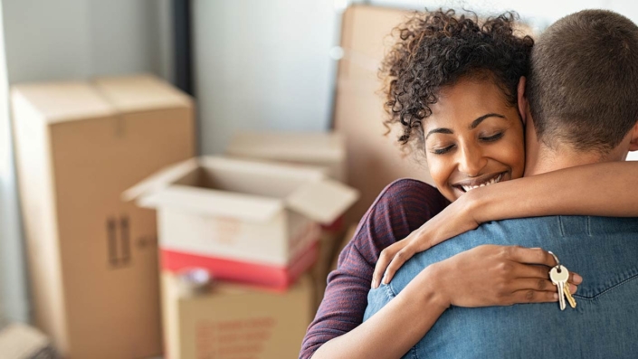 Woman holding keys from new home and embracing man Woman holding keys from new home and embracing man