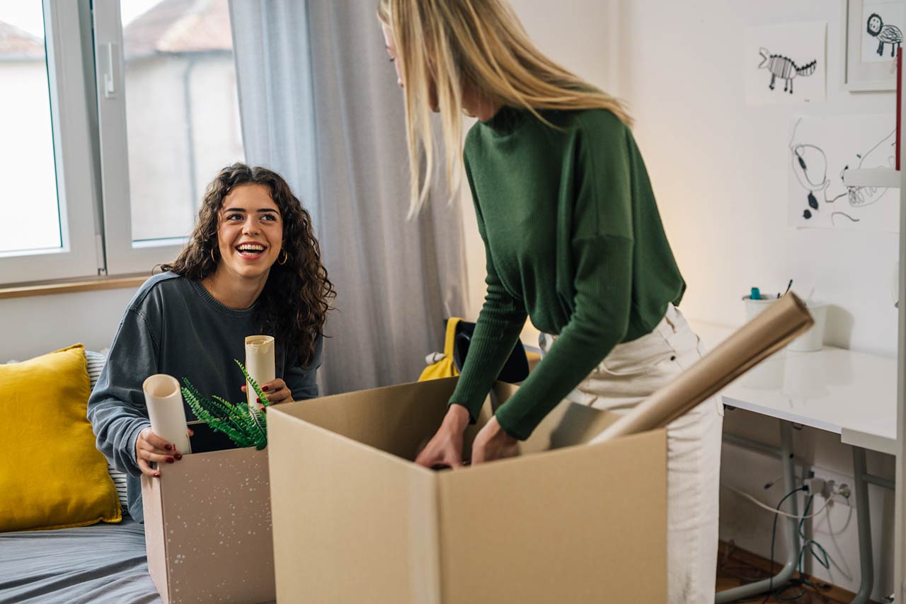 Caucasian female students unpacking in students room