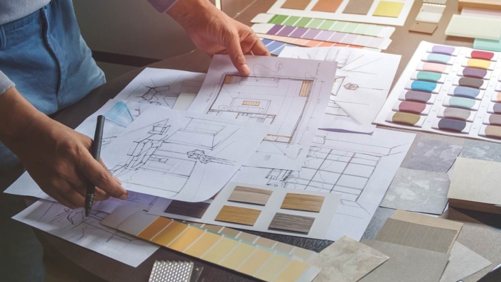 Interior designer working on hand drawing sketches on plan blueprints Interior designer working on hand drawing sketches on plan blueprints