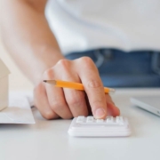 Close up of a mans hand with a pencil calculating with a small home model