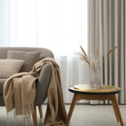 Grey sofa with pillows near window in stylish living room interior