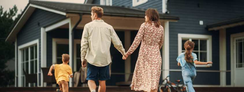 Young couple walking towards a country house with their two children