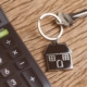 Home key with house keyring with black calculator on wooden table