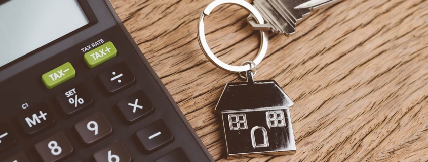 Home key with house keyring with black calculator on wooden table