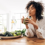 Young african american woman drinking green juice with reusable bamboo straw in loft apartment