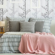 Feminine bedroom interior with forest inspired wallpaper and geometric bedding