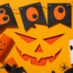 Paper decorations for Halloween on orange background, top view
