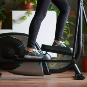 A womans legs training on smart elliptical trainer indoors at home in daylight with natural light