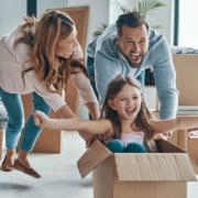 Cheerful young family smiling and unboxing their stuff while moving into a new apartment