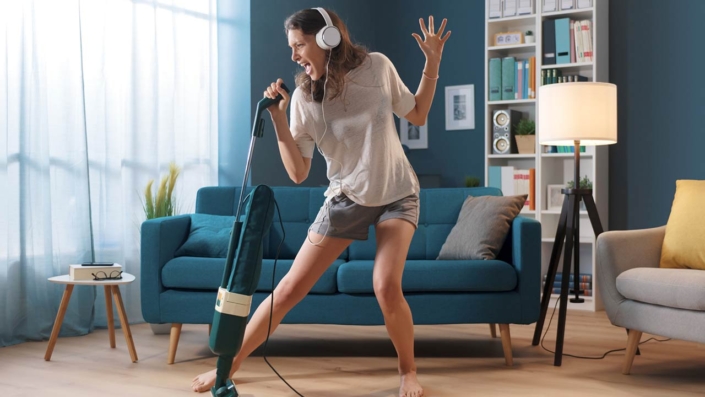 Cheerful woman cleaning up her home and singing, using the vacuum cleaner as a microphone Cheerful woman cleaning up her home and singing, using the vacuum cleaner as a microphone