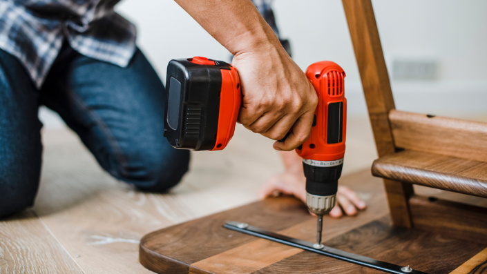 Man using hand drill to assemble a wooden table Man using hand drill to assemble a wooden table