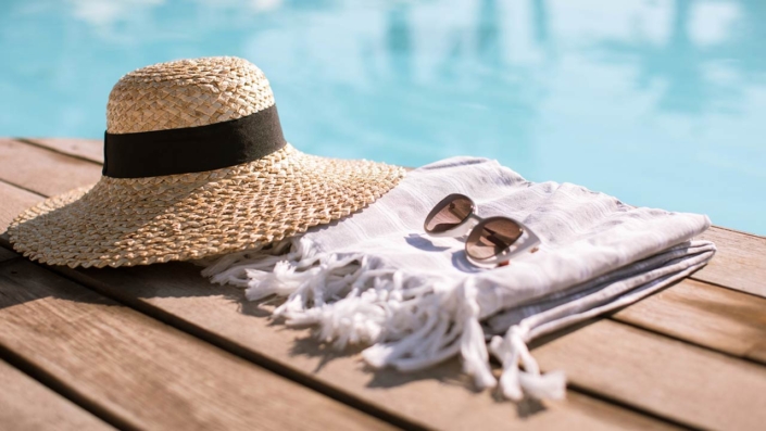Sunglasses and straw hat on the wooden floor at the pool Sunglasses and straw hat on the wooden floor at the pool